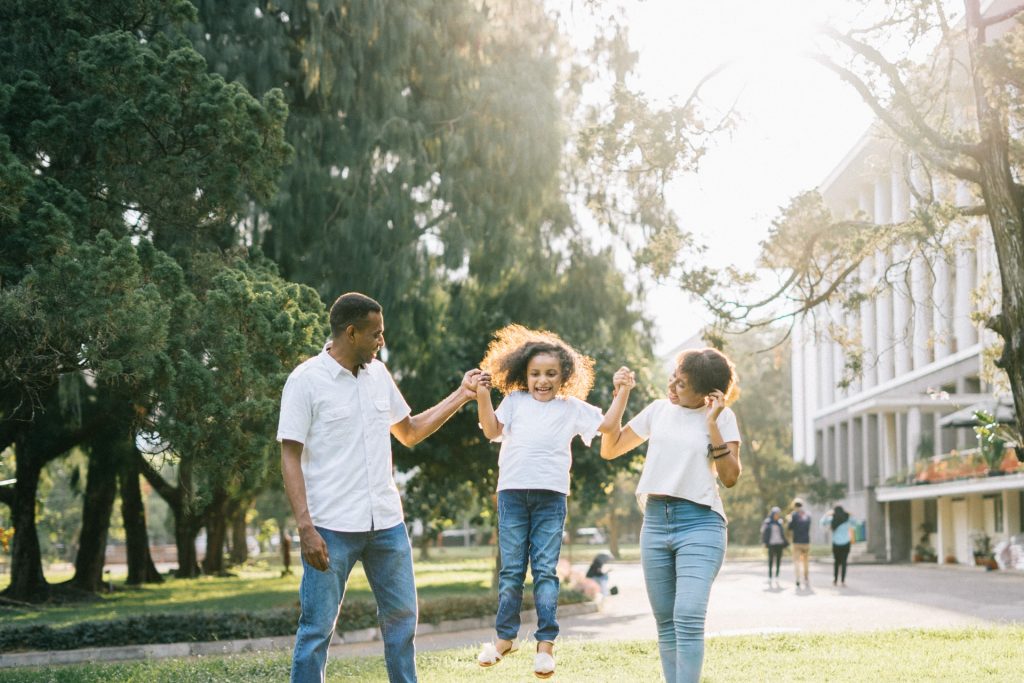 Parents and Child playing outside in front of a school
